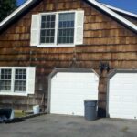 before construction photo showing old and rotten wood shingle and garage, driveway view