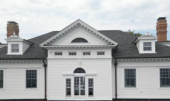 White clapboard colonial with dormers and twin chimneys