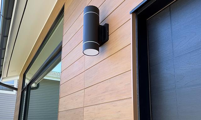 Close detail of dark panel siding and exterior lighting