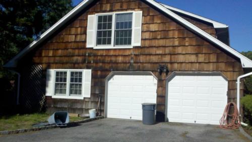 before construction photo showing old and rotten wood shingle and garage, driveway view
